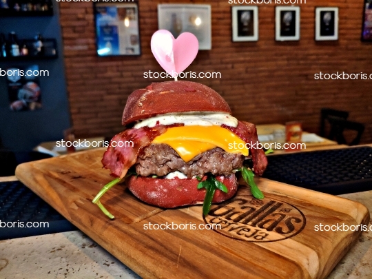 A hamburger in a red bread with a heart on it during valentine\'s day.