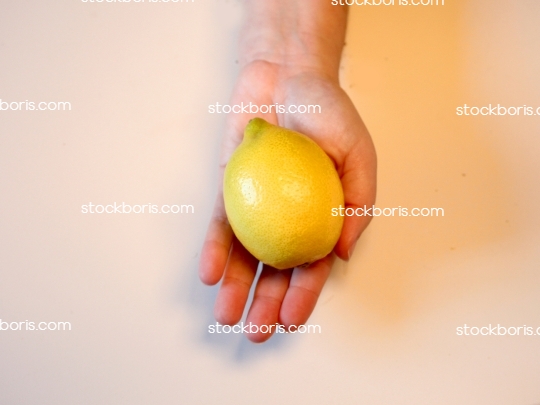 A hand holding a lemon.