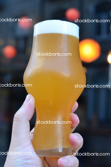 A hazy craft beer glass with a hand.