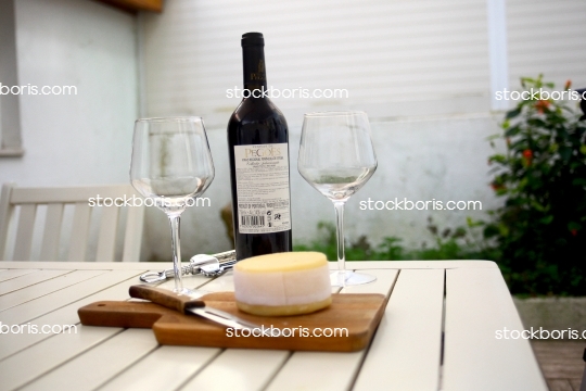 A wine bottle, glasses and Serra da Estrela cheese over a table.