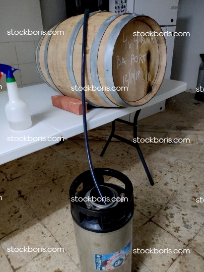 A wood cask with craft beer feeding a beer keg