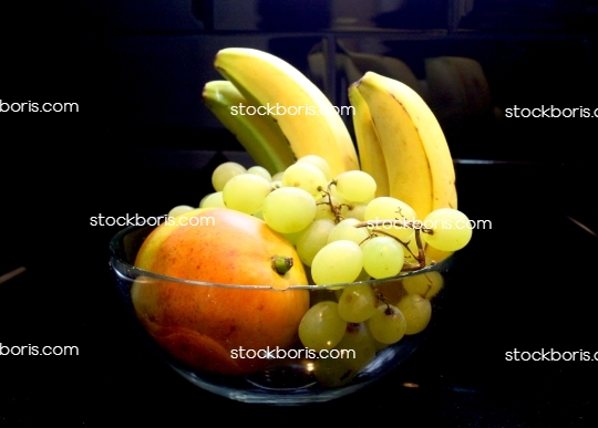 Bananas, grapes and papaya inside a bowl.