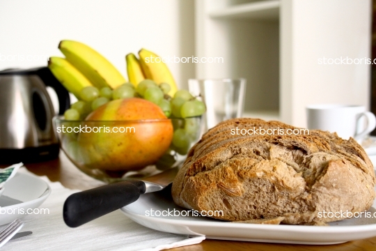 Breakfast table with bread, bananas, grapes and papaya