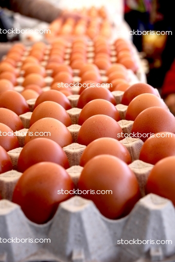 Dozens of brown eggs in boxes at a market.