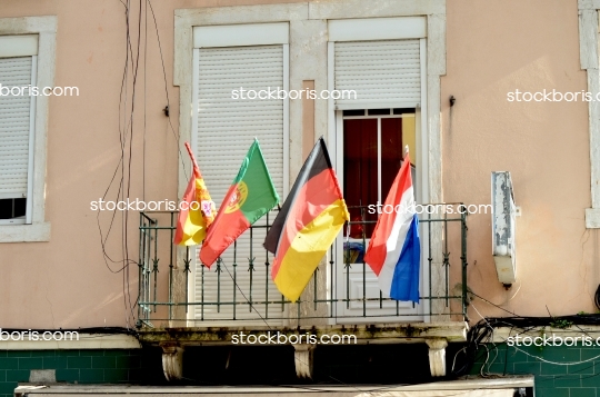 Flags of spain, portugal, germany and france in a balcony.