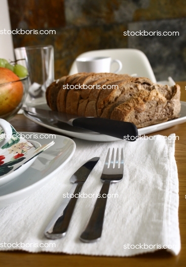 Fork and knife on a breakfast table with a bread.