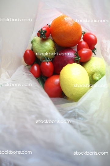 Fruits in a bag. Lemon, tomatoes, apples and orange in a plastic bag.