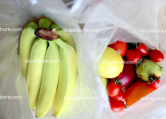 Fruits in a bag. Lemon, tomatoes, bananas, apples and orange in a plastic bag.