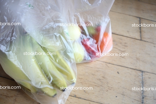 Fruits inside plastic bags. Bananas, lemons, tomatoes.