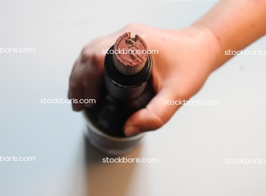 Hand holding a wine bottle from top.