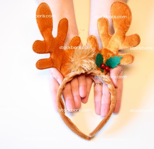 Hands holding a Christmas decoration reindeer arch.