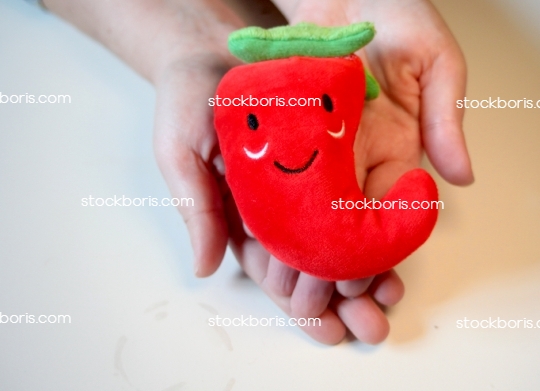 Hands with a smilling red pepper plush. Happy and good mood.