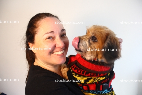 Happy woman with a puppy brown dog with a big tongue in her arms.