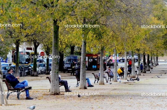 People sitting on benches waiting relaxing at a park.