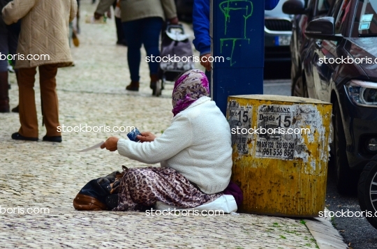 Poor miserable woman in the street with a scarf over her face.