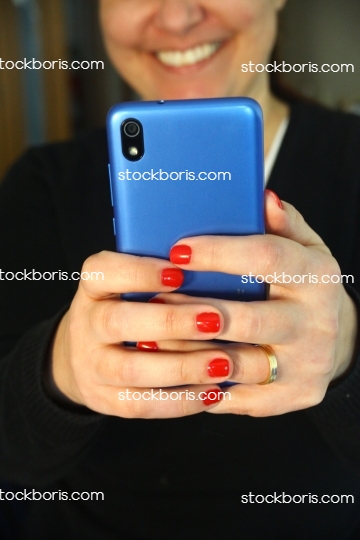 Smiling happy woman with a blue cell phone in her hands.