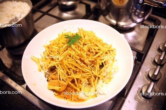 Strogonoff with potato sticks dish over a stove.