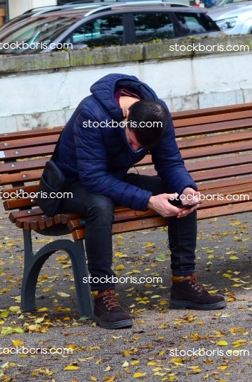 Tired man during coronavirus pandemics, sitting on a bench.