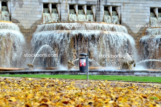 Water fountain, with statues and yellow leaves on the floor.