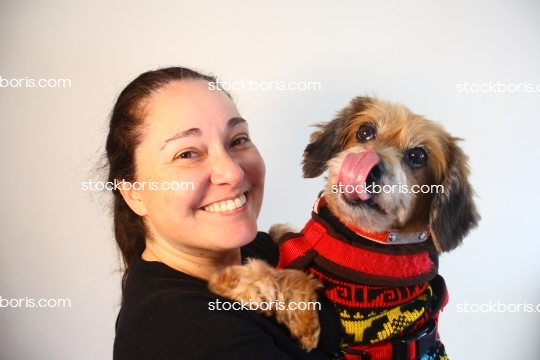 Woman with a puppy brown dog with a big tongue in her arms.