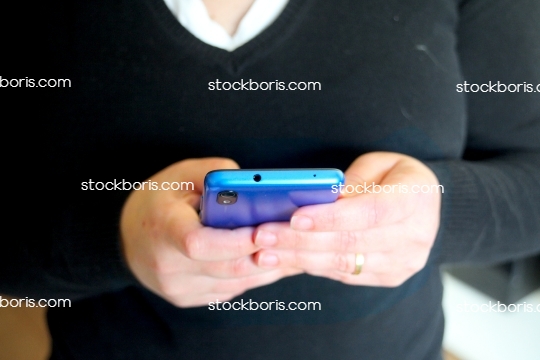 Woman\'s hands with a blue cell phone typing.